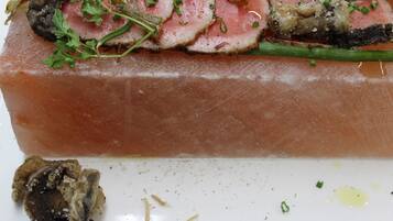 A dish with sliced meat, herbs, and mushrooms on a white plate.