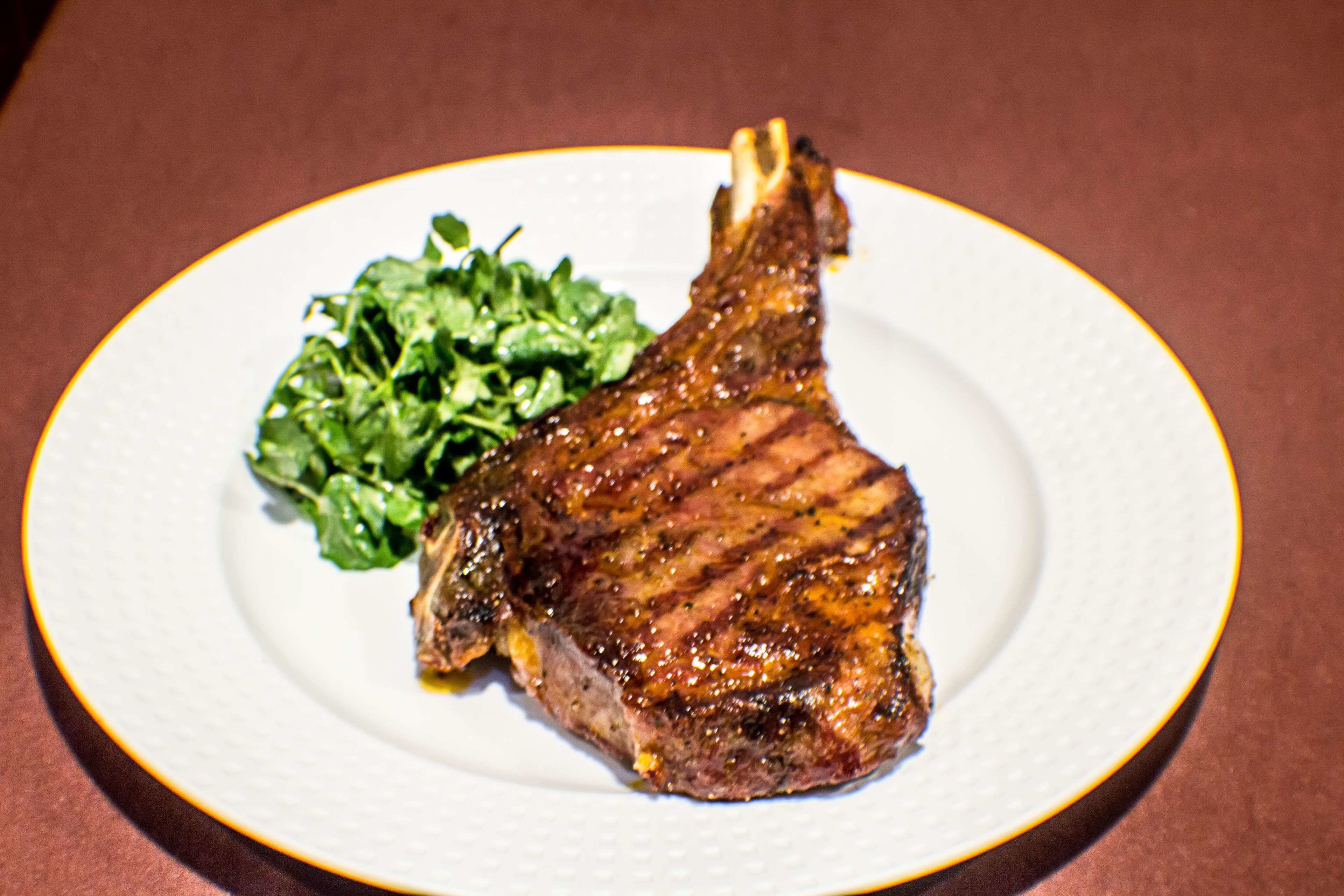 A plate with a grilled steak and greens.