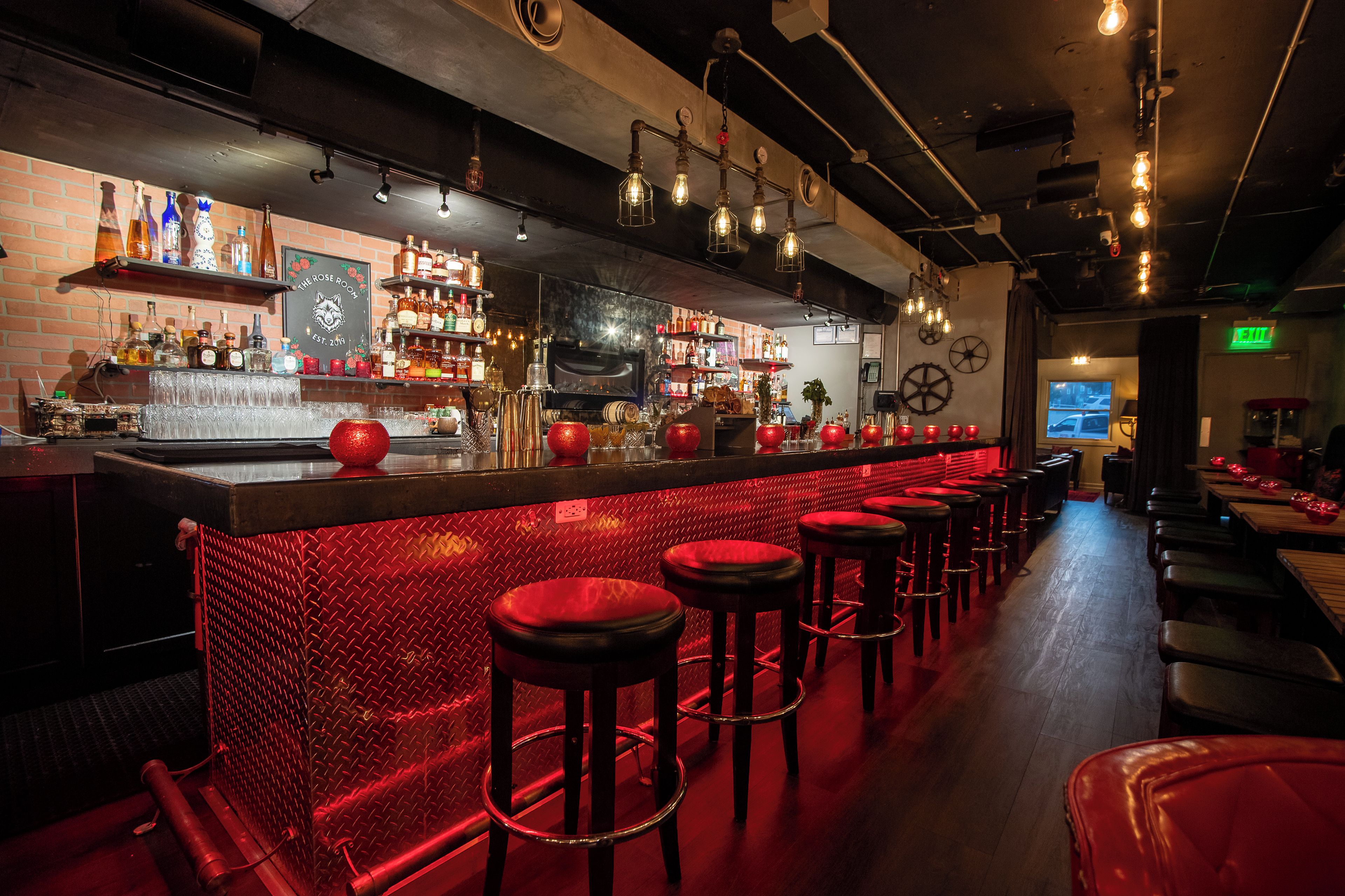 A bar area with stools, a bar counter, and shelves stocked with bottles.