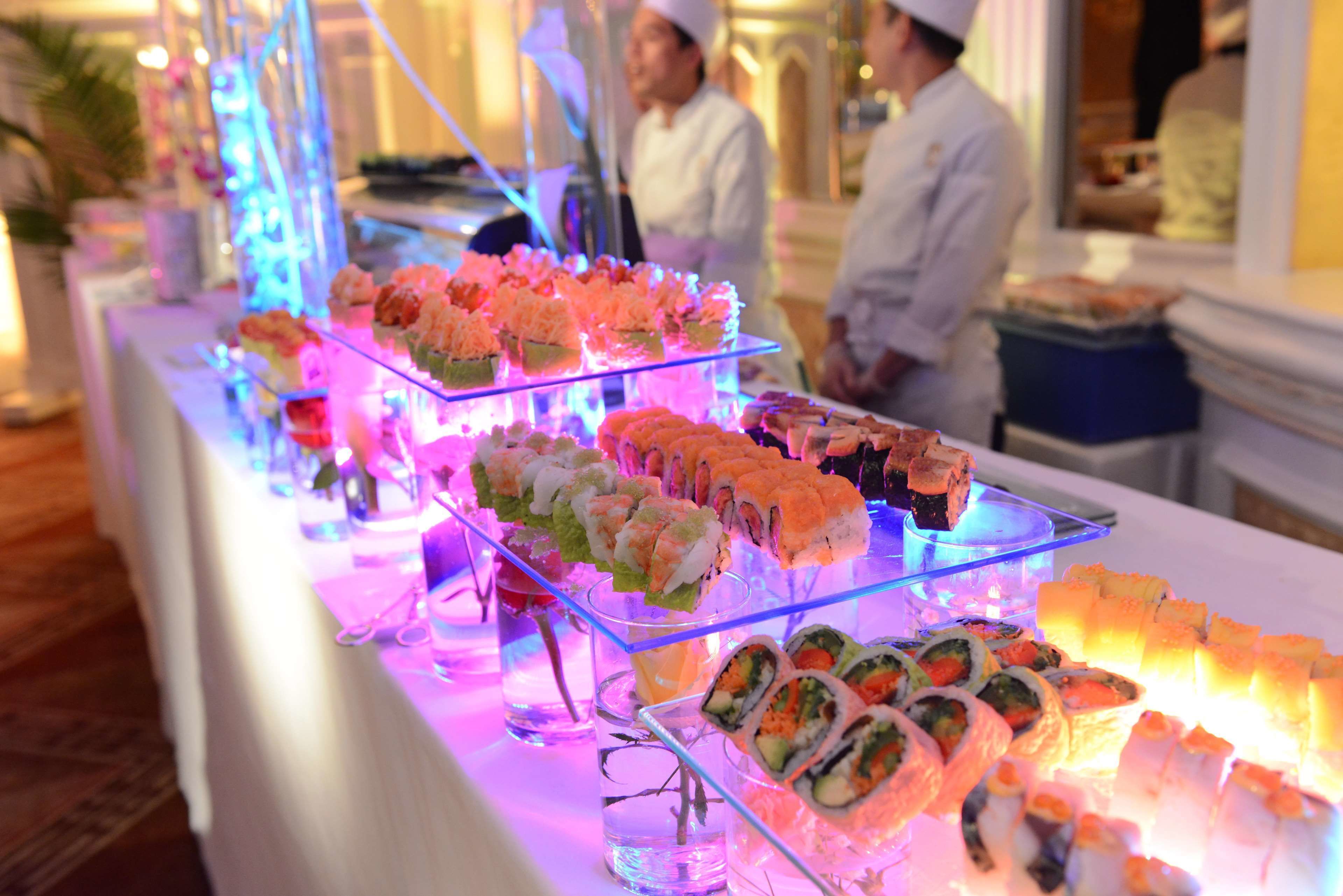 A buffet with various sushi options displayed on glass stands.