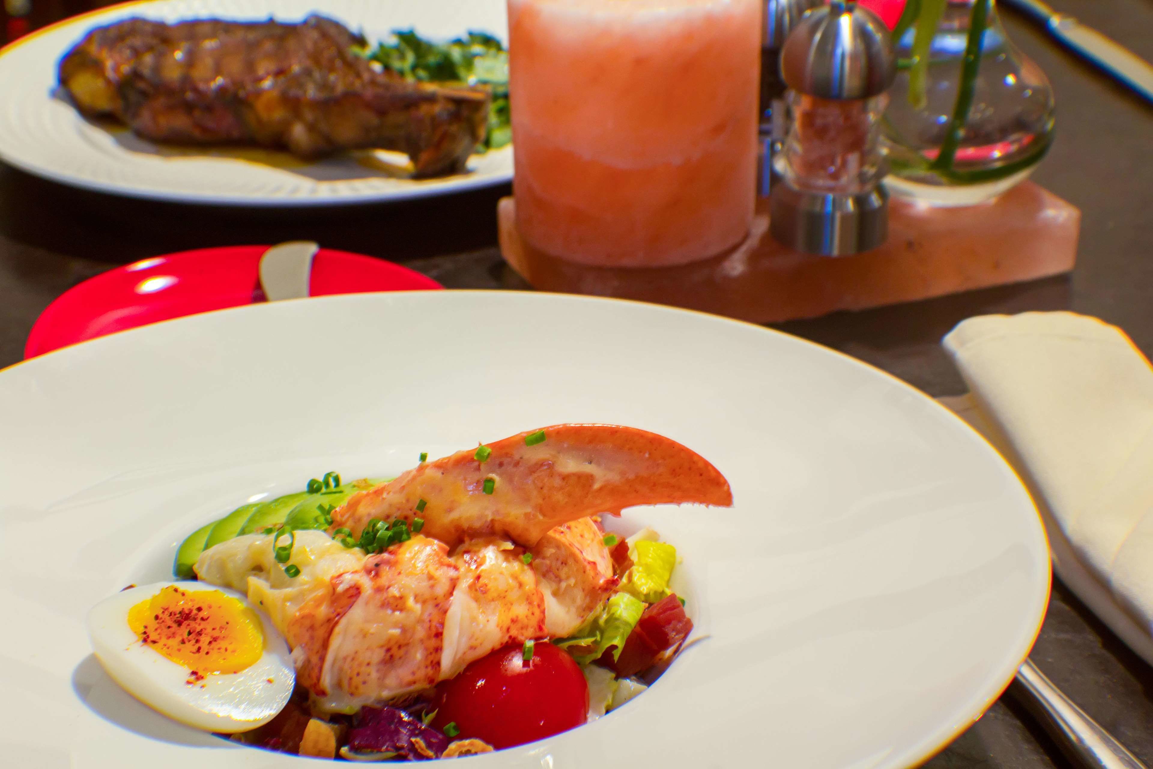 A plate of lobster with vegetables and a boiled egg.