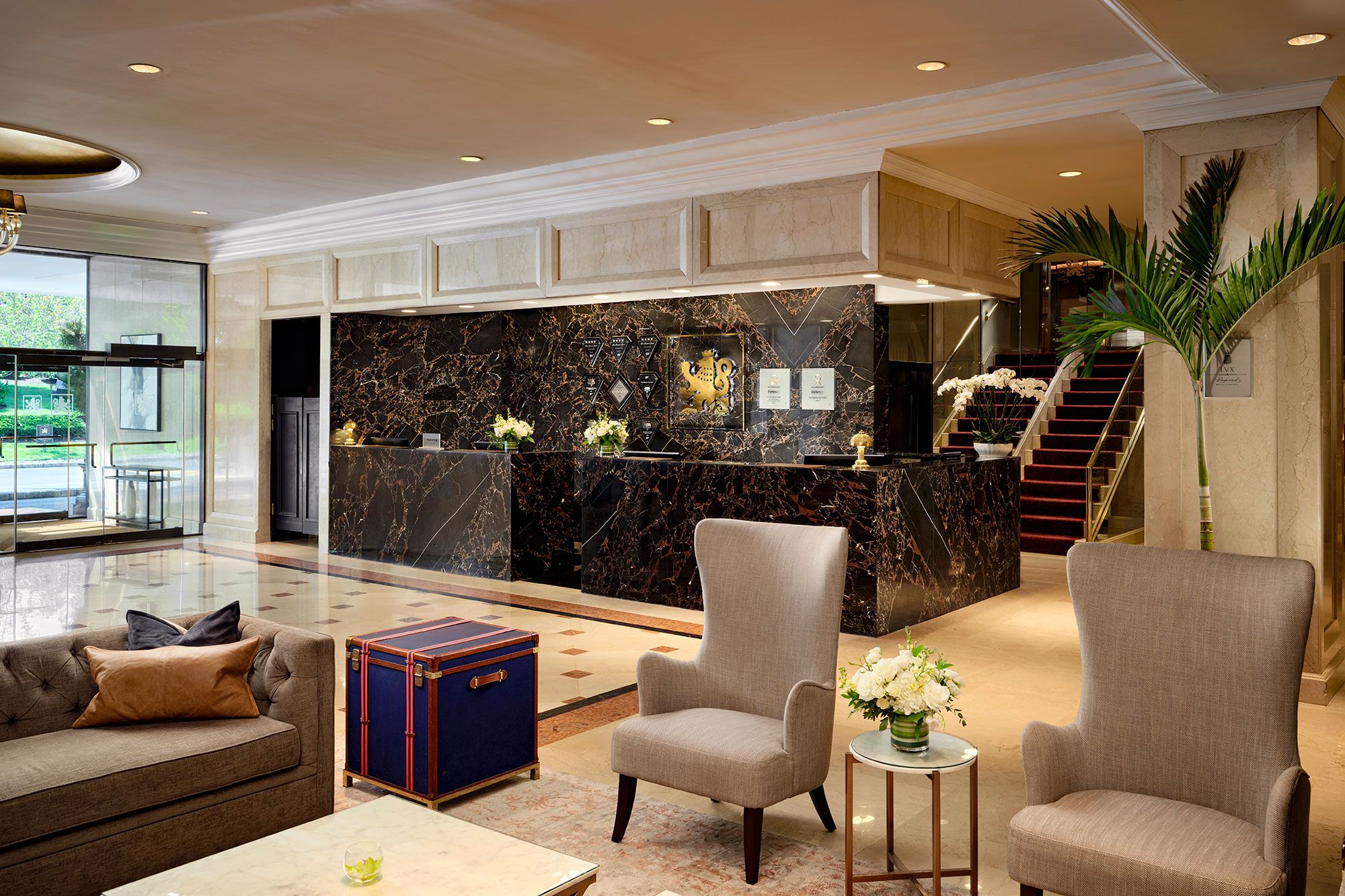 A lobby with a reception desk, seating area, and a staircase.