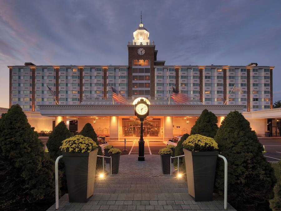 A hotel with a central clock tower, multiple floors, and a well-lit entrance.