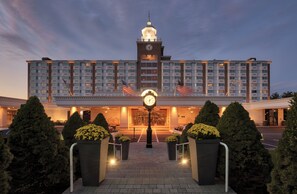 A hotel with a central clock tower, multiple floors, and a well-lit entrance. - The Garden City Hotel (Garden City)