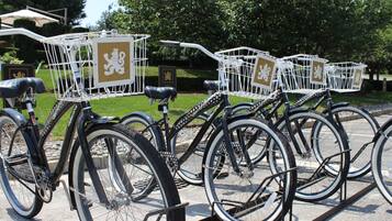 A row of bicycles with white baskets and brown signs, parked on a concrete surface.