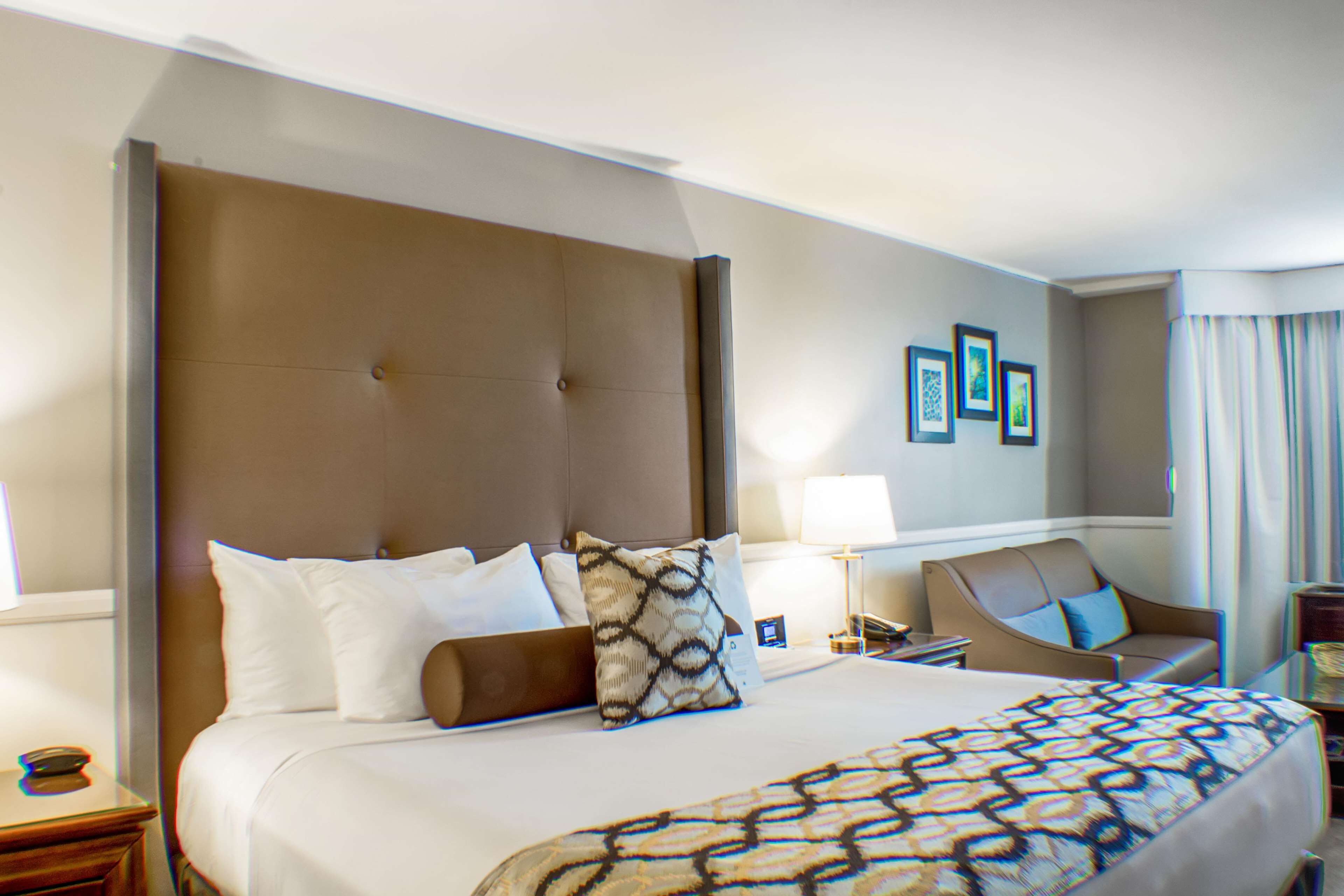 Une chambre d’hôtel avec un grand lit, une chaise, un bureau et une lampe.