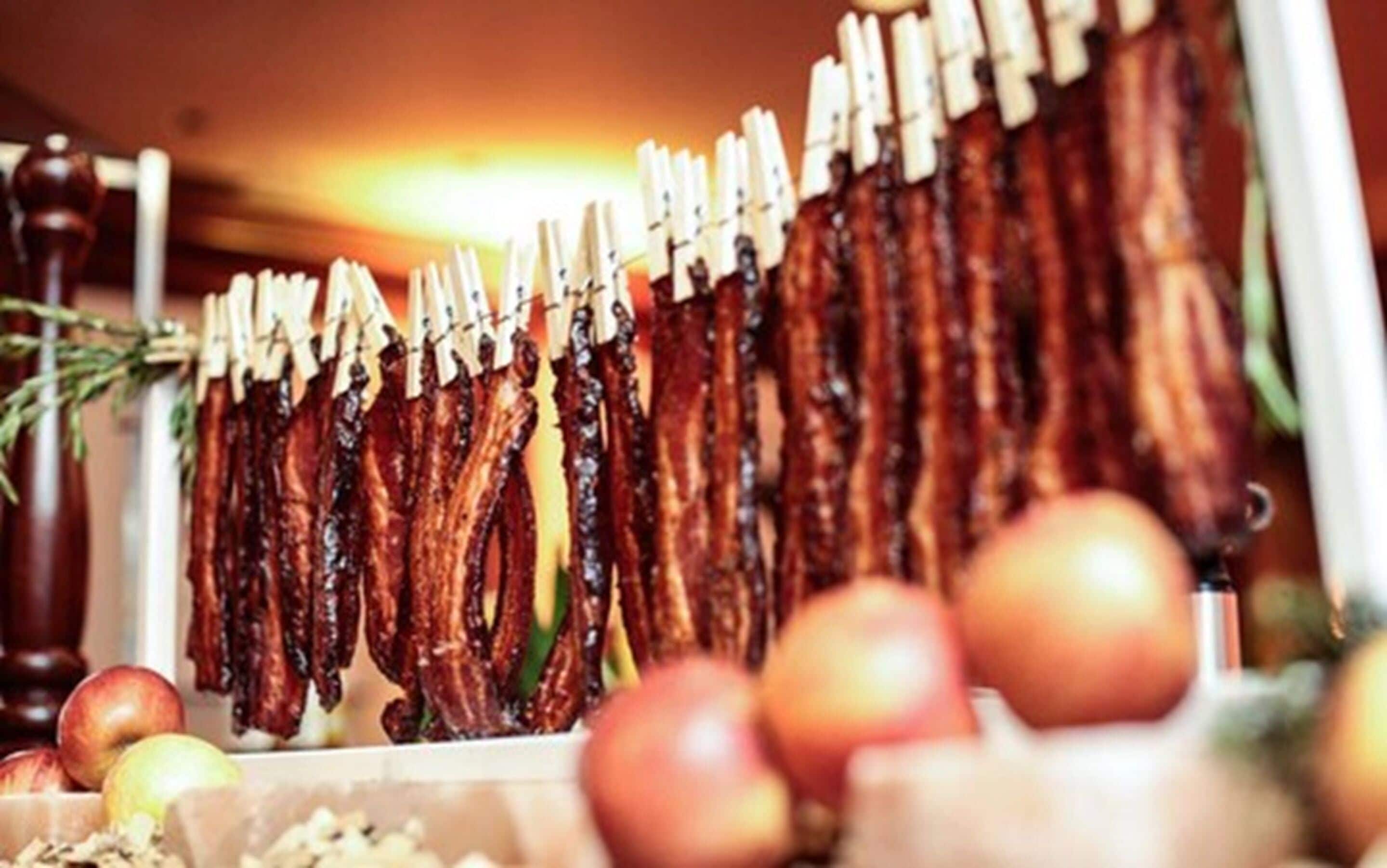 Geräuchertes Fleisch hängt an Holz-Klemmen.