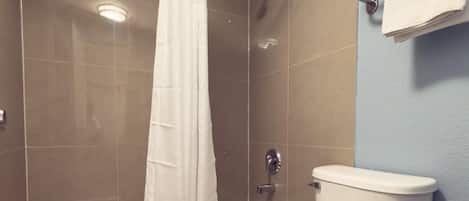 Un baño con bañera, inodoro y cortina de ducha.