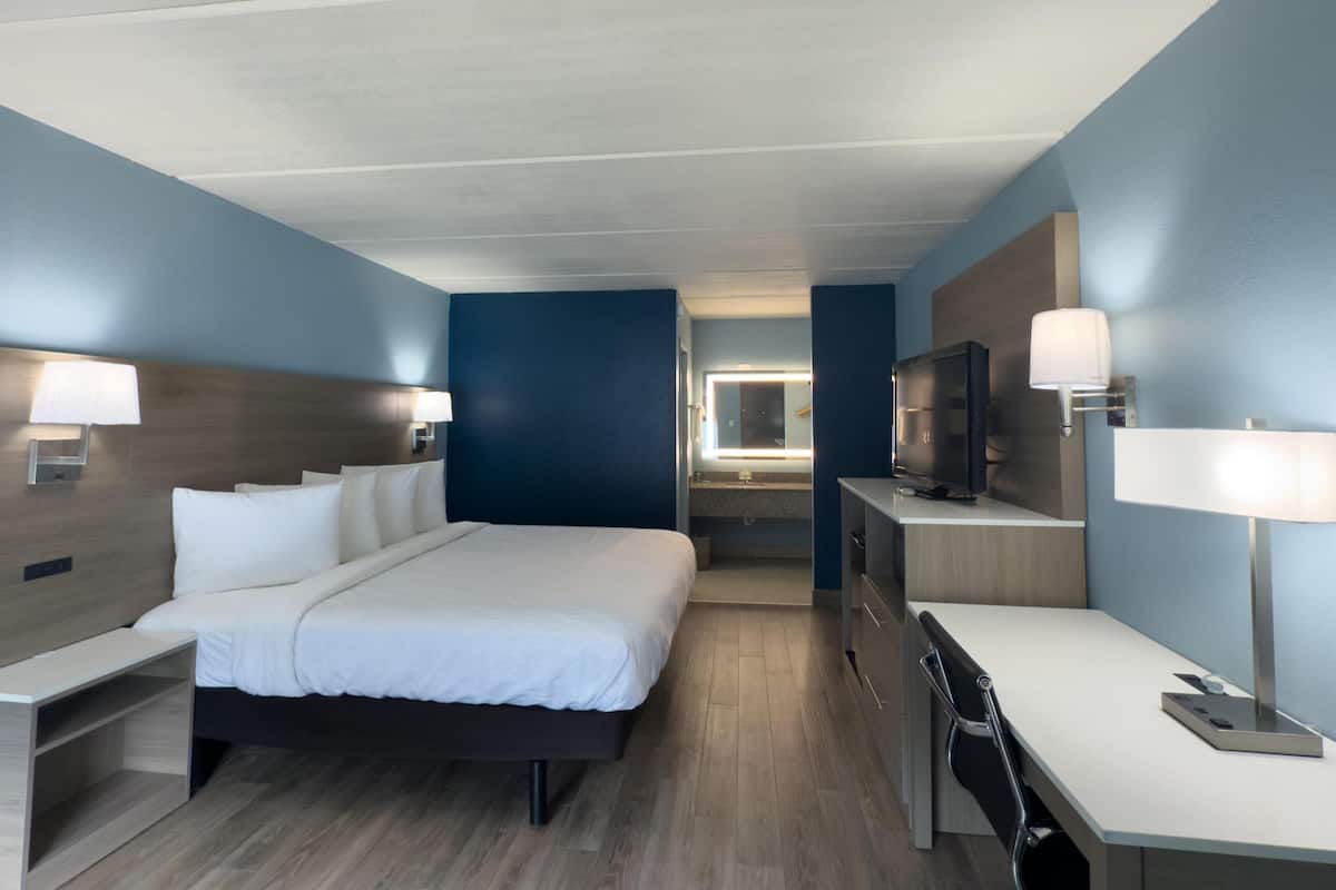 A modern hotel room with a bed, desk, and TV.