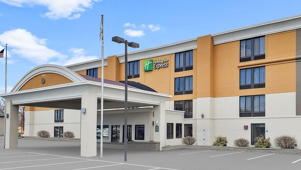 A Holiday Inn Express building with a covered entrance, multiple windows, and a parking lot. - Holiday Inn Express Rochester - Greece by IHG (Rochester)