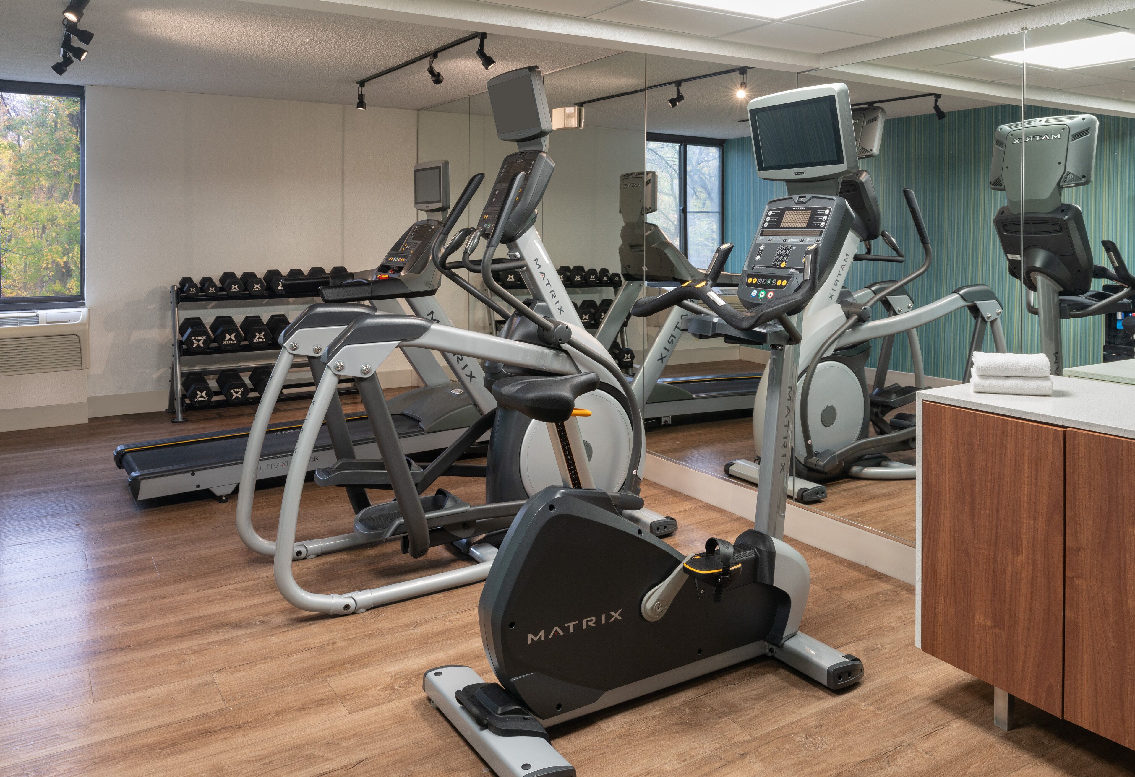 A gym with various exercise equipment, including treadmills, an elliptical, and dumbbells.