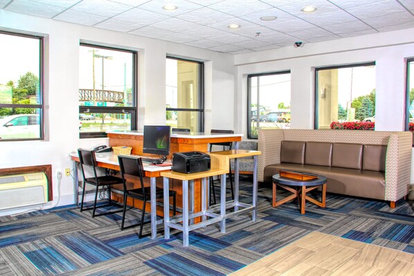 A hotel lobby with a reception desk, seating area, and large windows offering views of the outside.