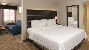 A hotel room with a large bed, a bedside table, a chair, a desk, and a mirror. - Holiday Inn Express Rochester - Greece by IHG (Rochester)