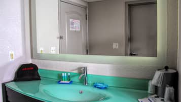 A bathroom with a sink, mirror, and toiletries.