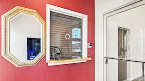 A room with a large mirror, a window with blinds, and a door with a glass panel. - HomeTowne Studios by Red Roof Yuba City Bonanza – Marysville (Yuba City)