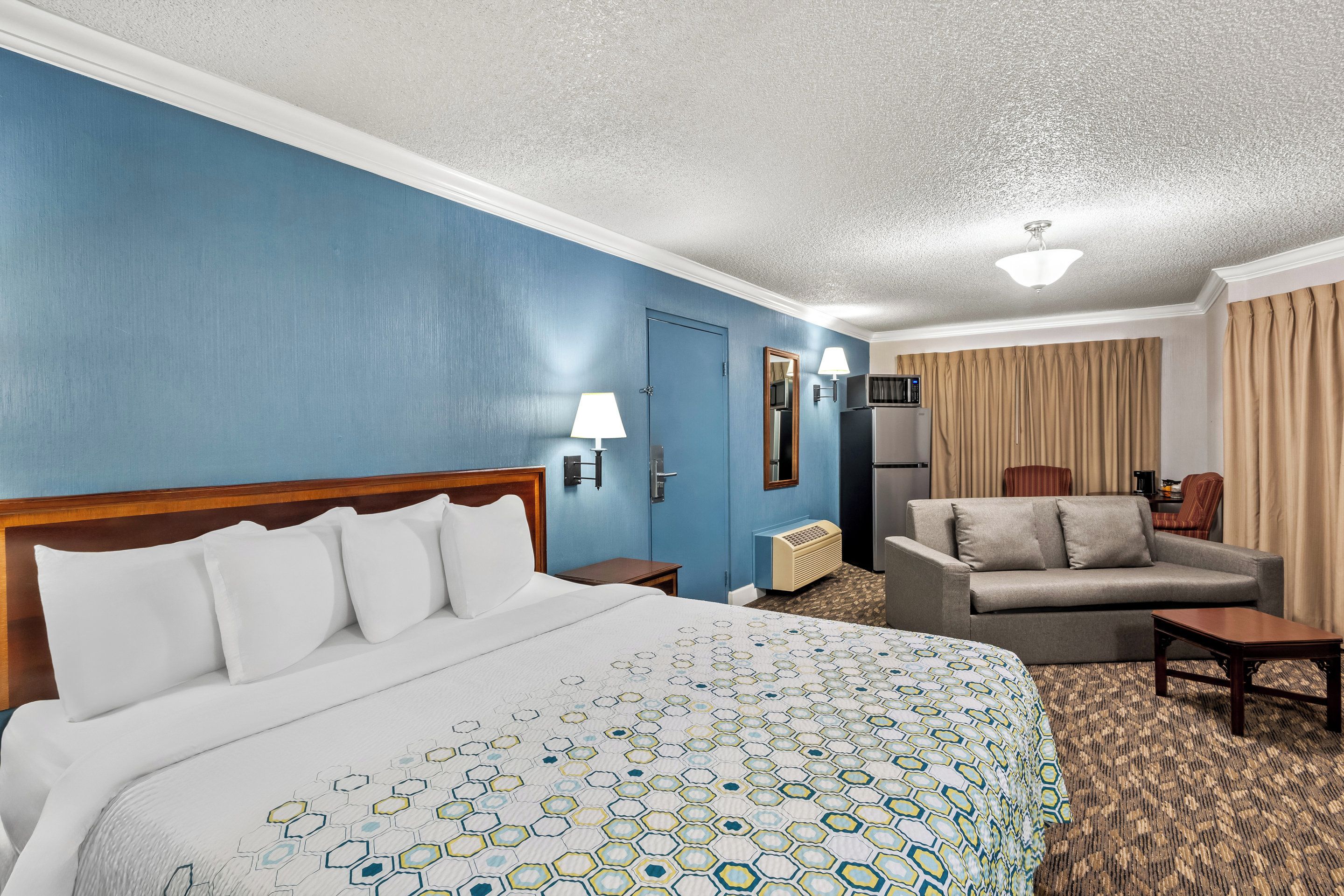 Una habitación de hotel con una cama grande, un sofá, un escritorio y una televisión.