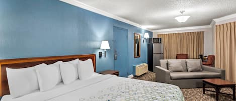 A hotel room with a large bed, a sofa, a desk, and a television.