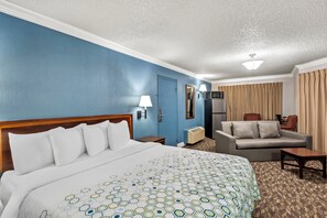 A hotel room with a large bed, a sofa, a desk, and a television.