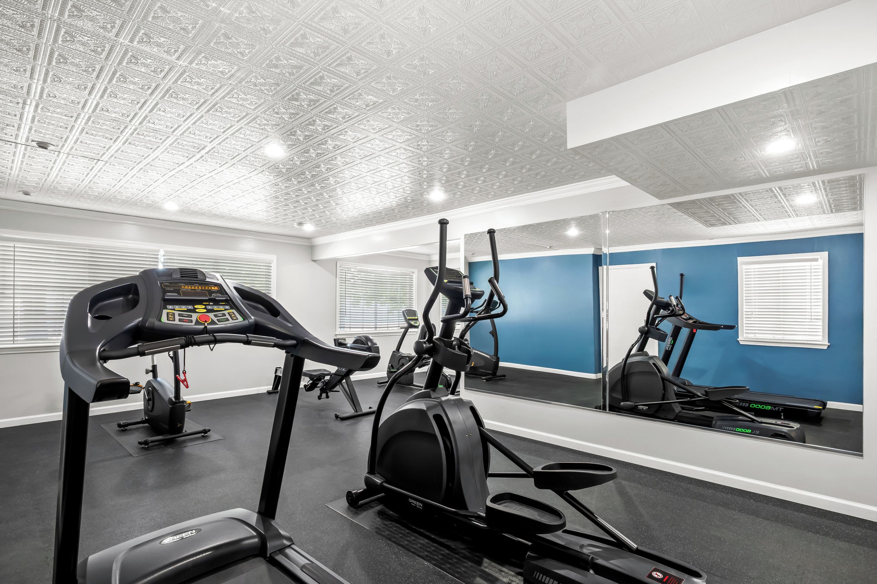 A gym with exercise equipment, a mirrored wall, and a blue accent wall.