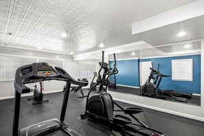 A gym with exercise equipment, a mirrored wall, and a blue accent wall.