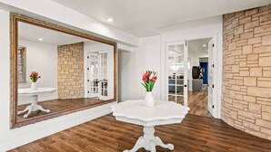 A room with a white pedestal table, a large mirror, and a vase with flowers. - HomeTowne Studios by Red Roof Yuba City Bonanza – Marysville (Yuba City)