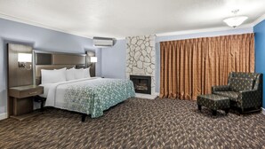 Une chambre d’hôtel avec un lit, une chaise, une cheminée et un mur en pierre.