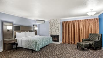 A hotel room with a bed, a chair, a fireplace, and a stone wall.
