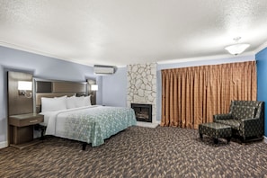 A hotel room with a bed, a chair, a fireplace, and a stone wall.