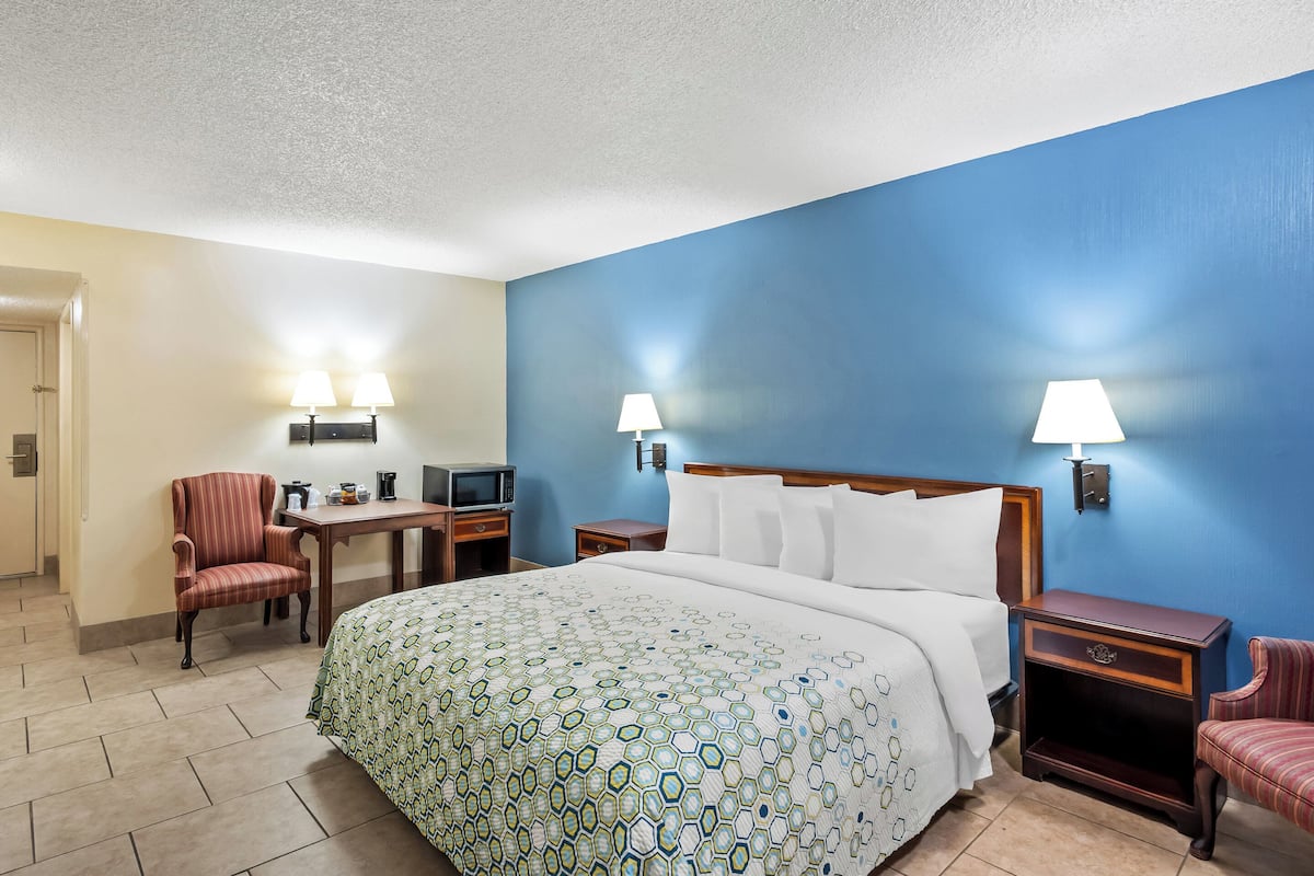 A hotel room with a large bed, two bedside tables, a desk with a chair, and a television.