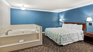 A hotel room with a large bathtub, a bed with a patterned bedspread, and two bedside lamps. - HomeTowne Studios by Red Roof Yuba City Bonanza – Marysville (Yuba City)