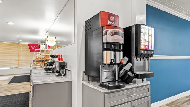 Une machine à café dotée d’un distributeur de dosettes de café de la marque Javo, d’une buse vapeur et d’un appareil pour faire mousser le lait.