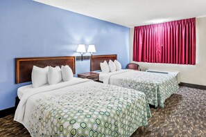 A hotel room with two beds, a nightstand, and a window with red curtains.