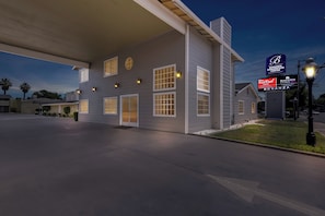 A hotel with a large signboard, multiple windows, and a well-lit exterior.