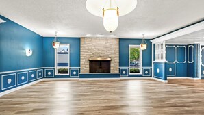 Une pièce spacieuse avec une cheminée en pierre, un plancher en bois et des murs bleus agrémentés de moulures blanches.