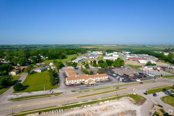 An aerial view of a commercial area with a large building labeled 'Shed', surrounded by parking lots and roads. - I-80 Inn & Suites (Davenport)