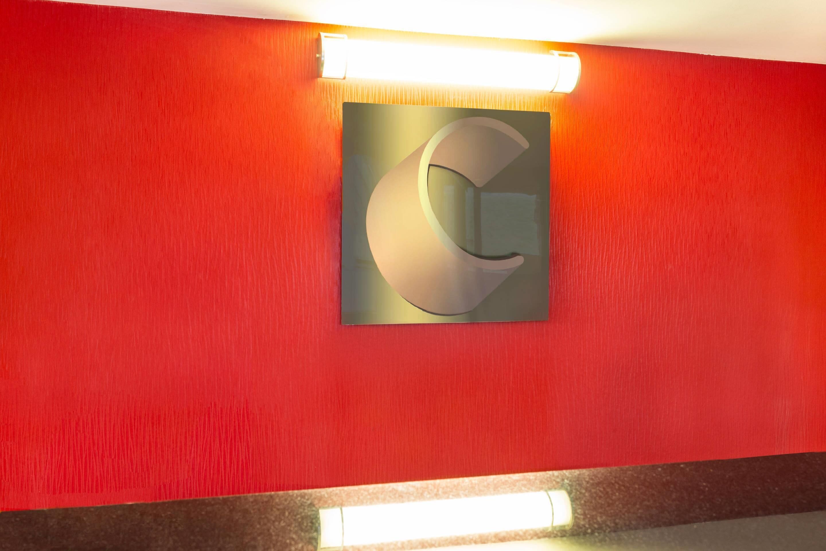 Un pasillo con una pared roja y una gran letra 'G' iluminada en la pared.