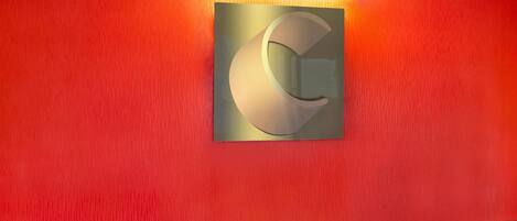 Un pasillo con una pared roja y una gran letra 'G' iluminada en la pared.