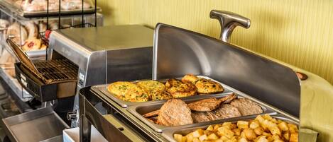 A buffet with various food options including baked goods, meats, and potatoes.