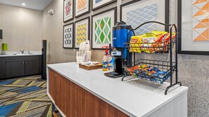 A hotel reception area with a coffee station, snack bar, and framed artwork on the wall. - Holiday Inn Express & Suites Lakeland South by IHG (Lakeland)