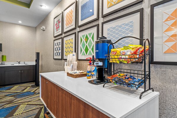 A hotel reception area with a coffee station, snack bar, and framed artwork on the wall. - Holiday Inn Express & Suites Lakeland South by IHG (Lakeland)