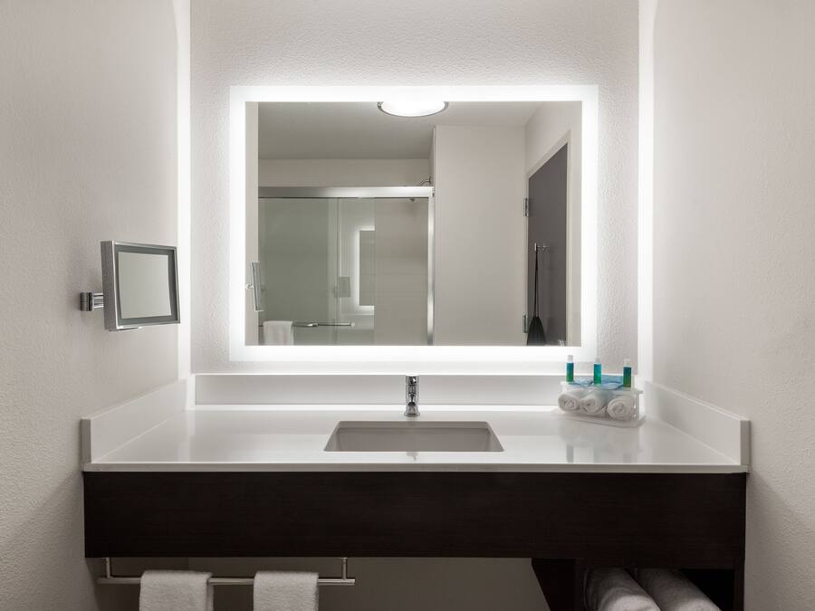 A modern bathroom with a white sink, dark vanity, and a large mirror.