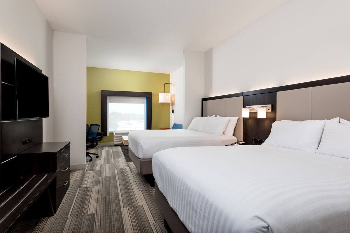 Een hotelkamer met twee bedden, een bureau, een televisie en een raam met uitzicht.