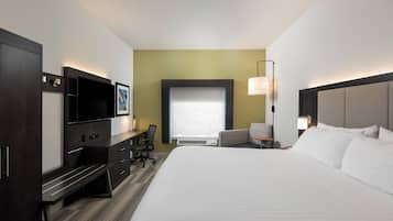 Habitación de hotel con cama, escritorio, silla, televisor y ventana.