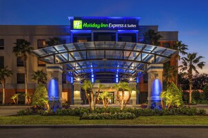 Edificio di un Holiday Inn Express & Suites con tettoia in vetro, palme e facciata ben illuminata.