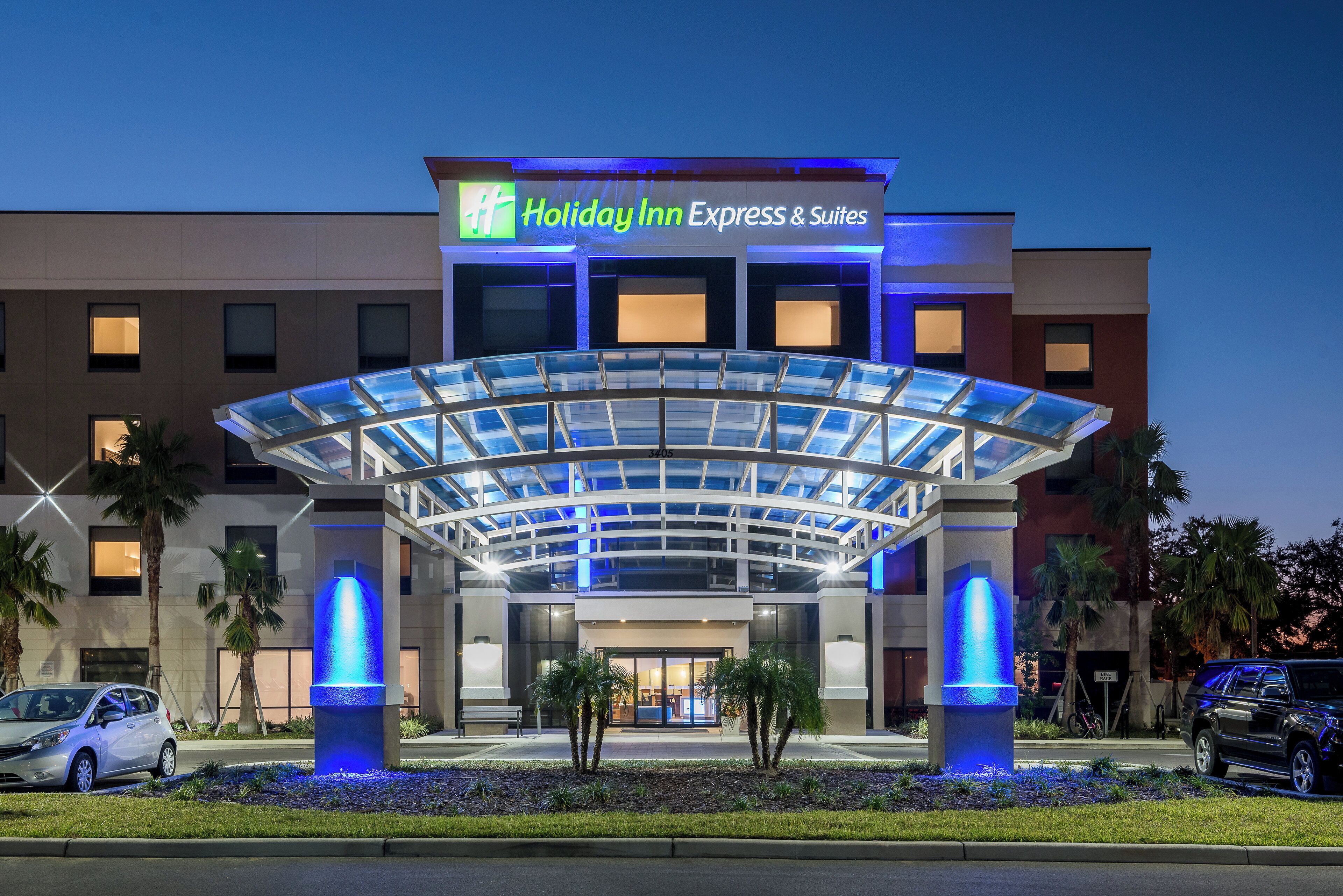 A Holiday Inn Express & Suites with a modern glass entrance and illuminated pillars.