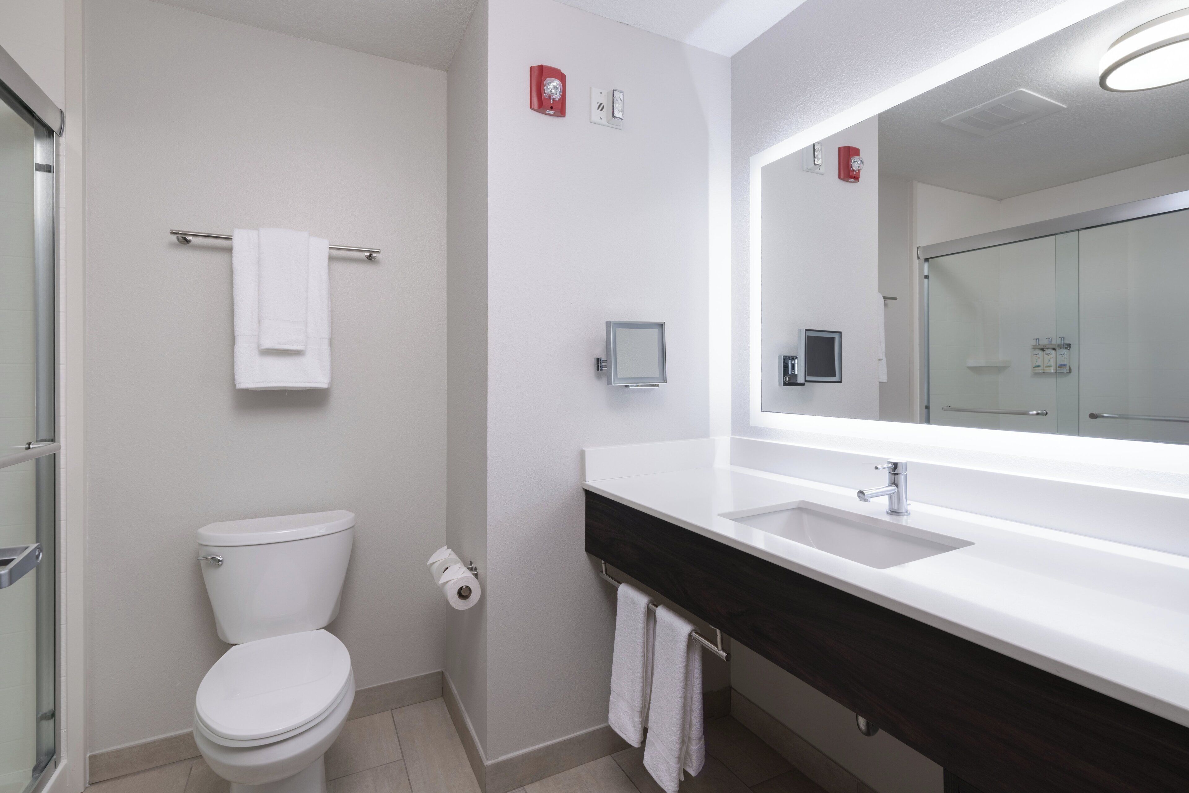Ein modernes Badezimmer mit Toilette, Waschbecken und einem großen Spiegel.