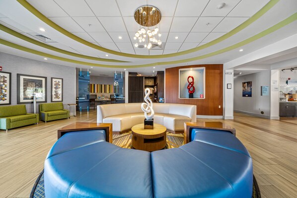 A modern lobby with a curved seating area, a central art piece, and a wooden reception desk. - Holiday Inn Express & Suites Lakeland South by IHG (Lakeland)