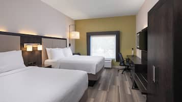 A hotel room with two beds, a desk, a chair, a TV, and a window with blinds.