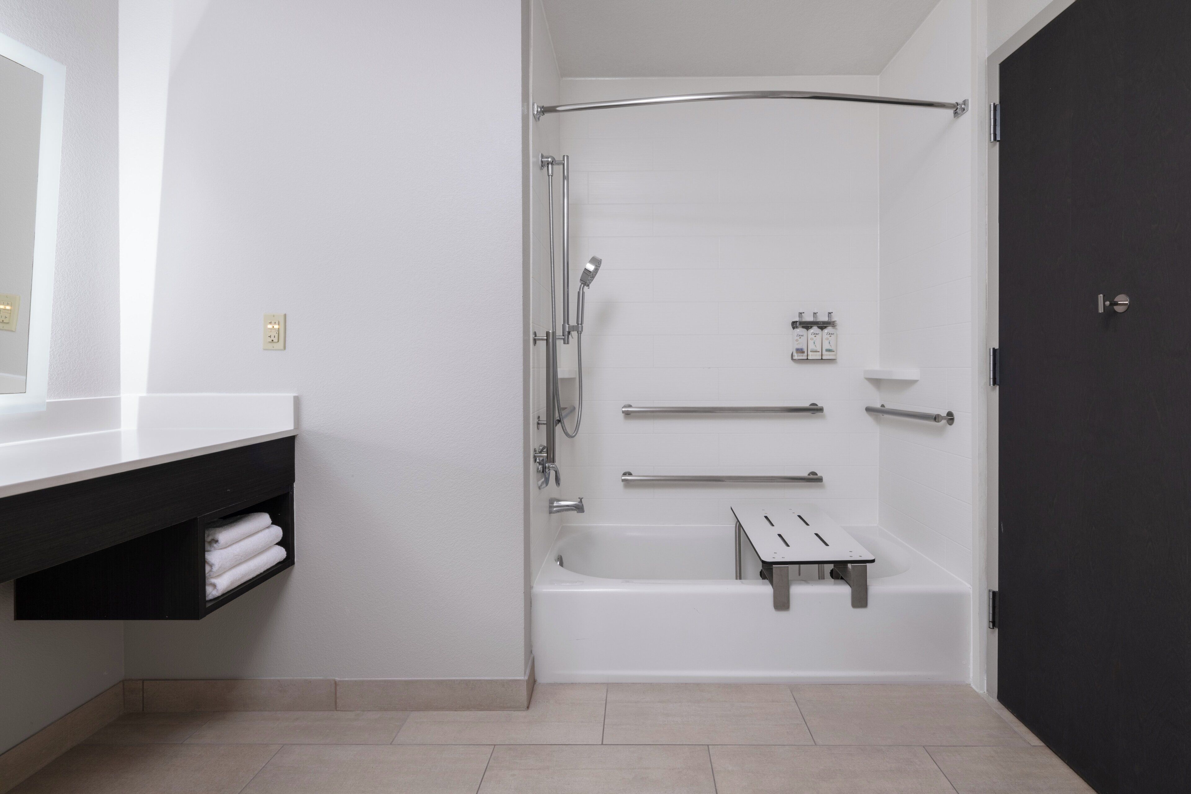 A modern bathroom with a bathtub, shower, and a dark door.