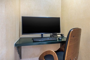 Work in comfort with a desk setup featuring a flat-screen monitor, keyboard, and mouse, paired with a comfortable chair.